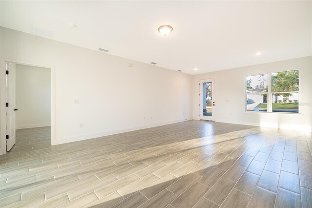 unfurnished room with wood finish floors, visible vents, and baseboards