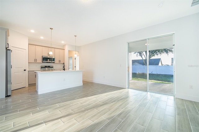 kitchen with baseboards, open floor plan, light countertops, appliances with stainless steel finishes, and decorative light fixtures