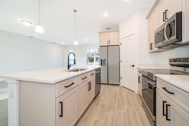 kitchen featuring pendant lighting, visible vents, appliances with stainless steel finishes, a sink, and an island with sink