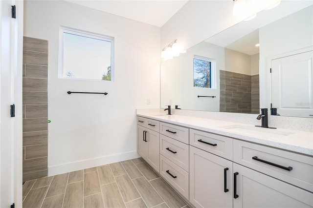 bathroom with double vanity, wood finish floors, a sink, and baseboards