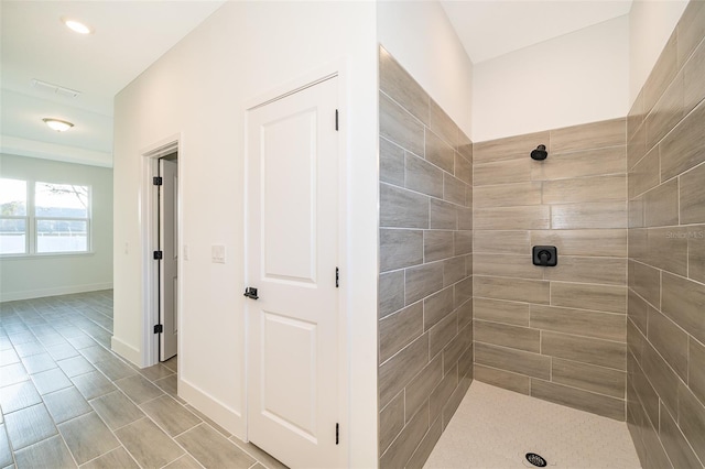 full bathroom with tile patterned flooring, a tile shower, and baseboards