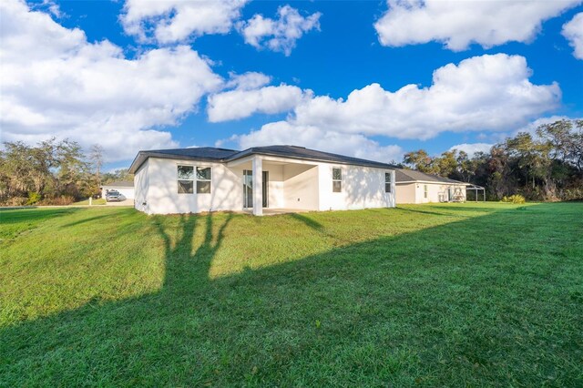 back of property with stucco siding and a yard