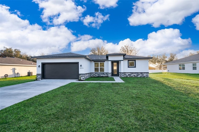 prairie-style house featuring a front lawn, concrete driveway, an attached garage, and stucco siding