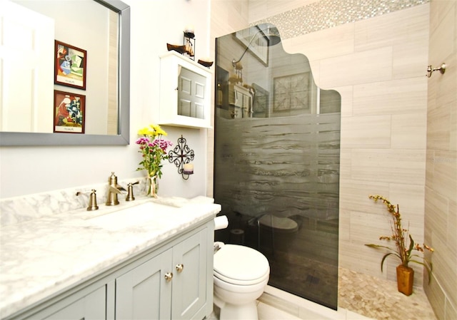 bathroom featuring vanity, toilet, and tiled shower