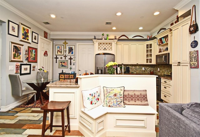 kitchen with stainless steel fridge, tasteful backsplash, a kitchen island with sink, cream cabinets, and a breakfast bar area