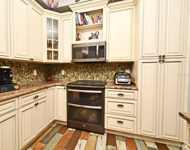 kitchen with cream cabinets, range with two ovens, and dark stone counters