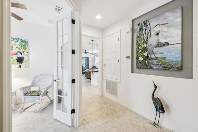 hall featuring light tile patterned floors and french doors