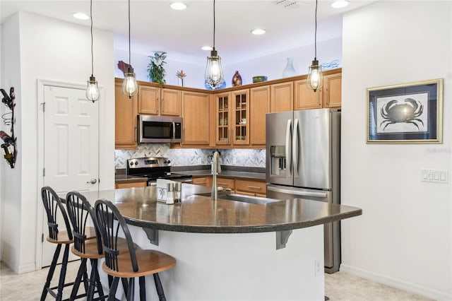 kitchen with sink, stainless steel appliances, tasteful backsplash, an island with sink, and a kitchen bar