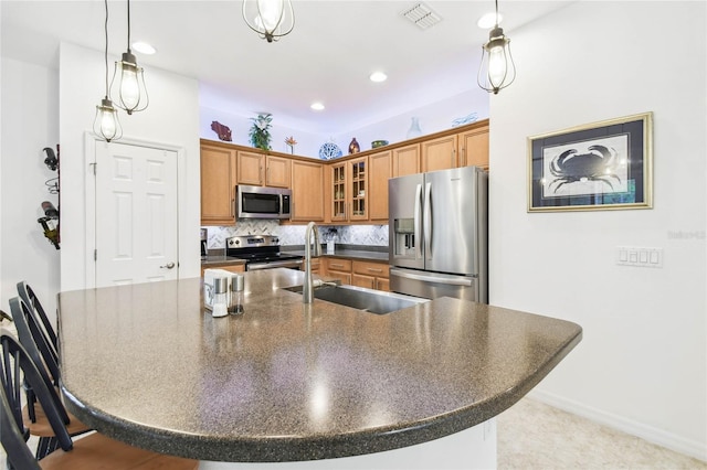 kitchen with pendant lighting, sink, decorative backsplash, appliances with stainless steel finishes, and a kitchen bar