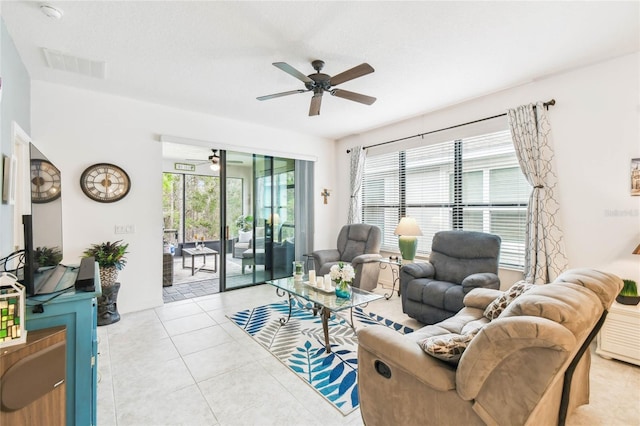 living room featuring ceiling fan, light tile patterned floors, and a textured ceiling