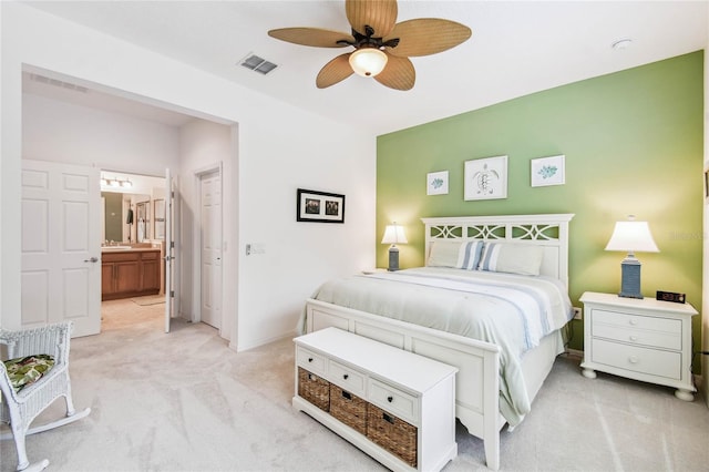 bedroom with ensuite bathroom, ceiling fan, sink, and light carpet