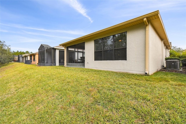 rear view of property with a sunroom, a yard, and central AC