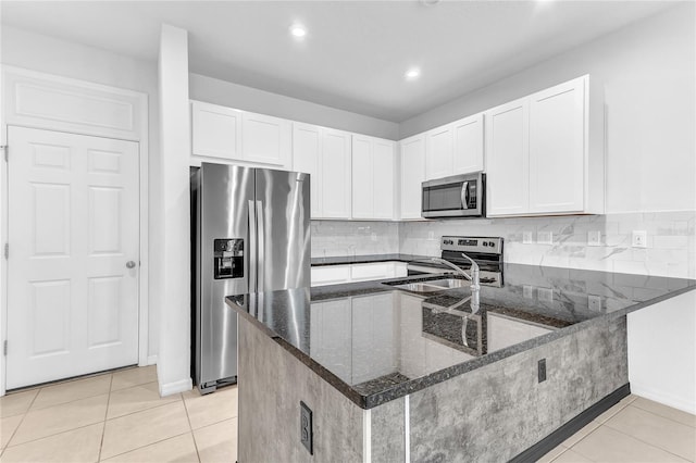 kitchen with white cabinetry, appliances with stainless steel finishes, dark stone countertops, and kitchen peninsula