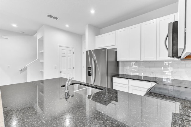 kitchen featuring sink, appliances with stainless steel finishes, white cabinetry, decorative backsplash, and dark stone counters