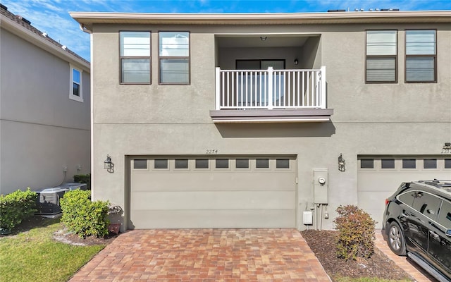 view of property with a garage, central AC, and a balcony