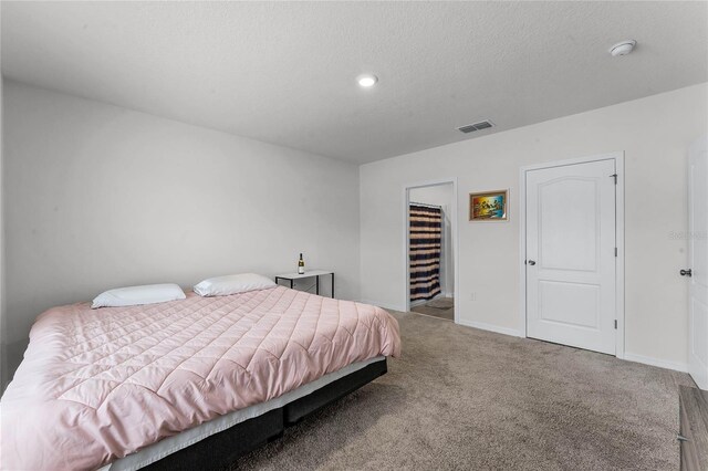 bedroom with carpet flooring, a textured ceiling, a walk in closet, and a closet