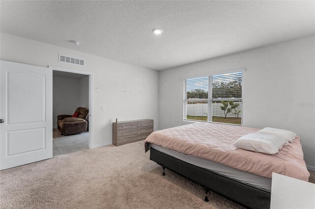 bedroom with light carpet and a textured ceiling