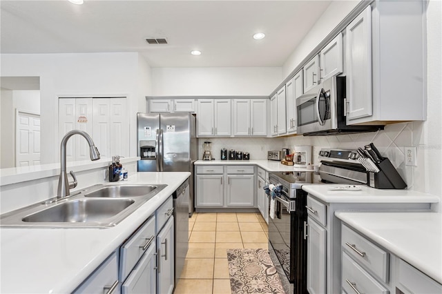 kitchen with gray cabinetry, sink, decorative backsplash, light tile patterned flooring, and stainless steel appliances