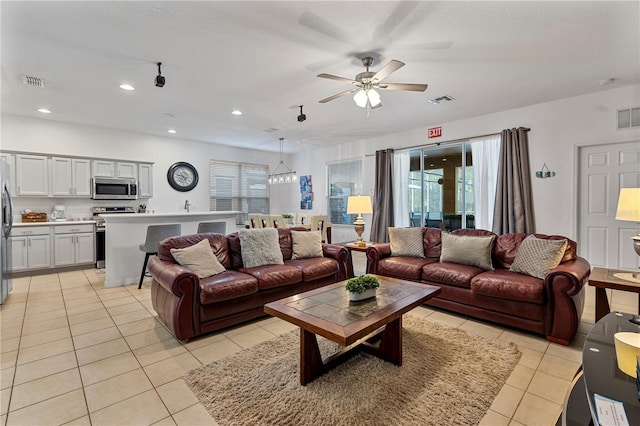 living room featuring plenty of natural light, light tile patterned flooring, and ceiling fan with notable chandelier