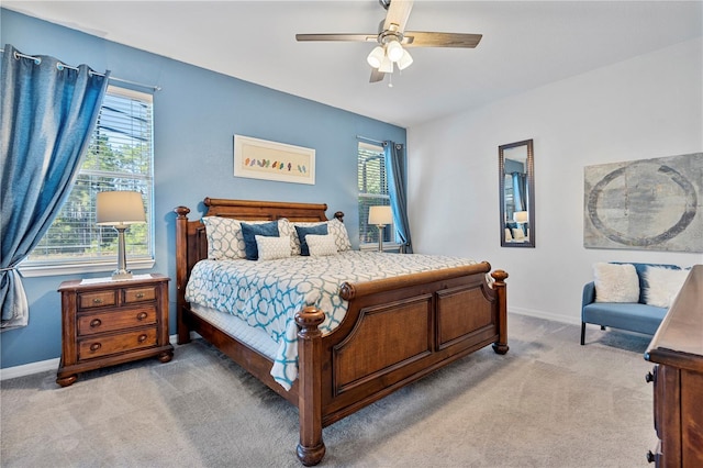 bedroom featuring multiple windows, light colored carpet, and ceiling fan