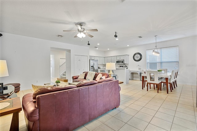 tiled living room featuring ceiling fan with notable chandelier