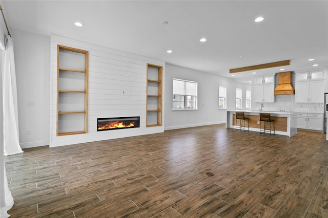 unfurnished living room with a large fireplace, built in features, and sink