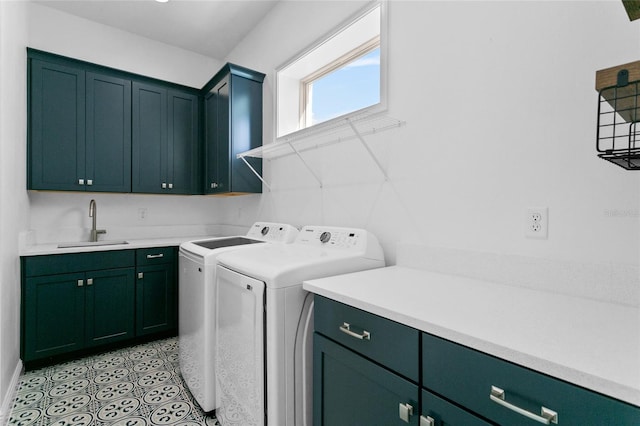 clothes washing area featuring washing machine and clothes dryer, sink, and cabinets