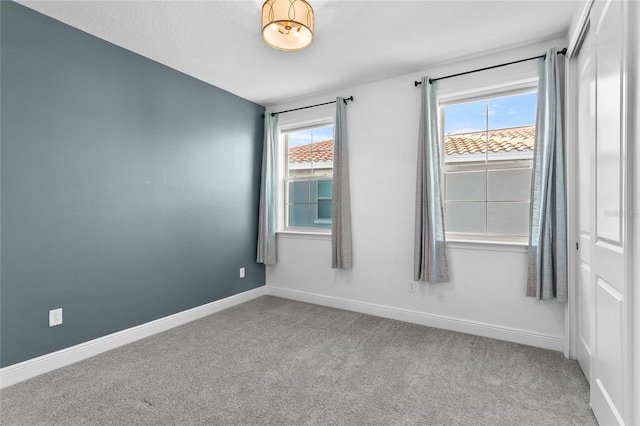 unfurnished room featuring carpet flooring, a textured ceiling, and a wealth of natural light