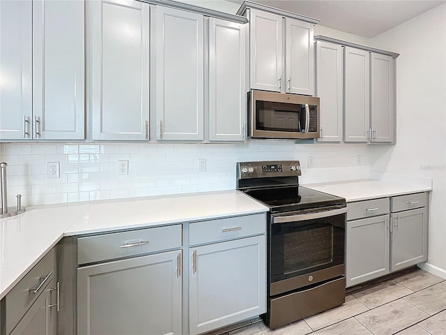 kitchen featuring stainless steel appliances, gray cabinets, and backsplash