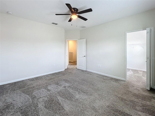 unfurnished bedroom with ceiling fan, carpet flooring, a closet, and a spacious closet