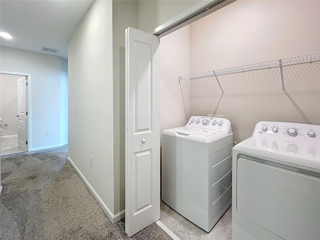 washroom with washing machine and clothes dryer and light carpet