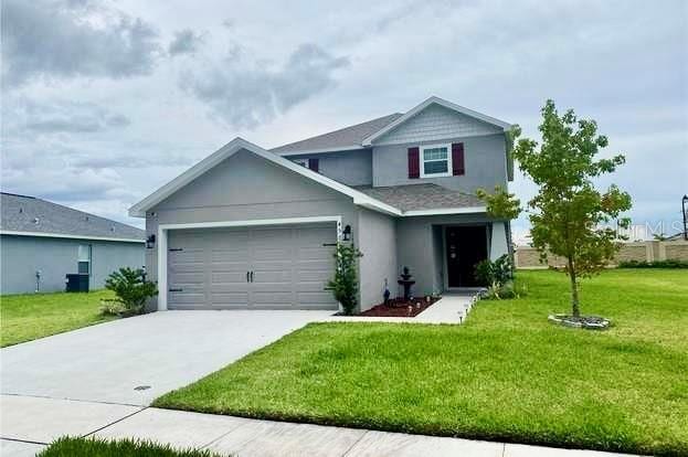 view of front facade featuring cooling unit, a garage, and a front lawn