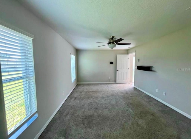 carpeted empty room featuring a wealth of natural light, a textured ceiling, and ceiling fan