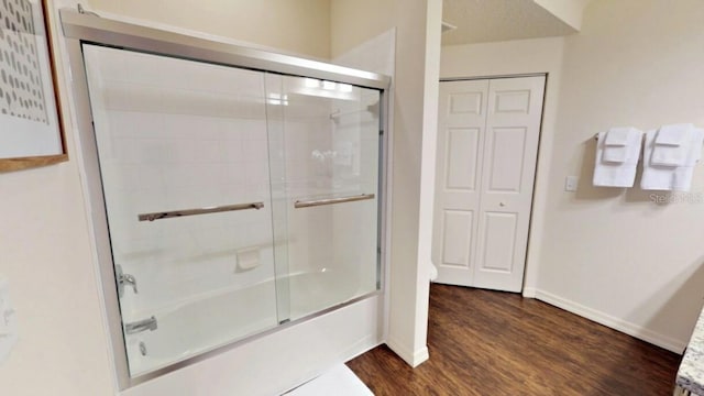 bathroom featuring enclosed tub / shower combo and wood-type flooring