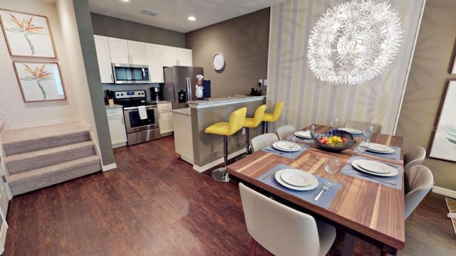 kitchen featuring dark hardwood / wood-style flooring, white cabinetry, stainless steel appliances, and a breakfast bar area