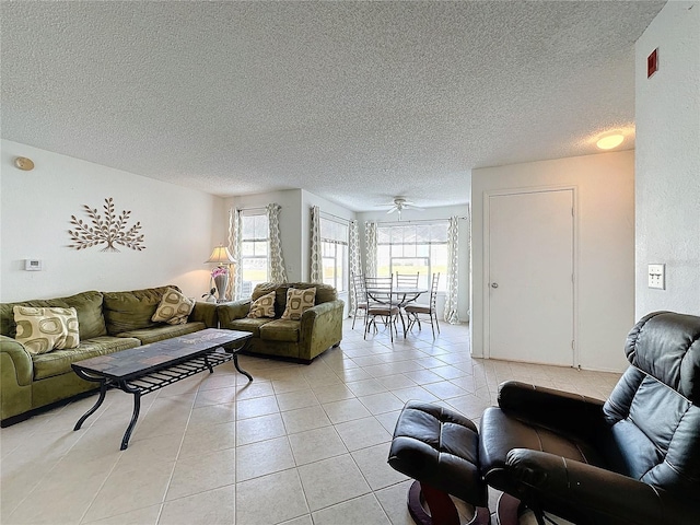 living room with ceiling fan, light tile patterned flooring, and a textured ceiling