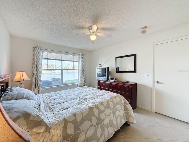 bedroom featuring ceiling fan, light tile patterned flooring, and a textured ceiling