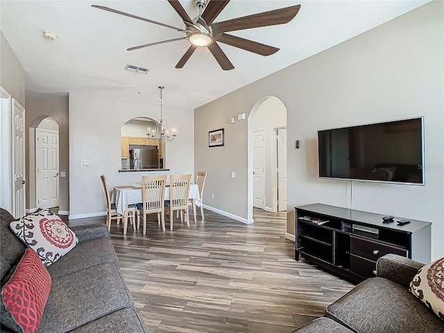 living room featuring ceiling fan with notable chandelier and dark hardwood / wood-style floors