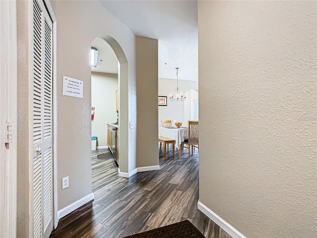 hallway featuring dark wood-type flooring and a notable chandelier