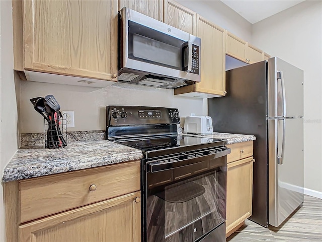 kitchen featuring light stone countertops, light brown cabinets, and stainless steel appliances