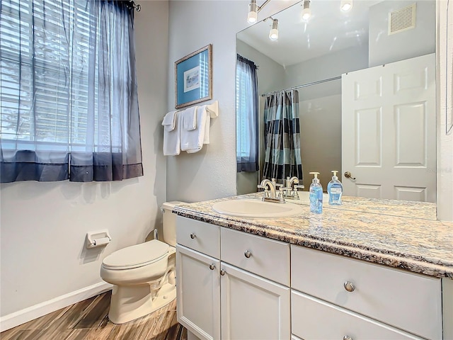 bathroom with hardwood / wood-style floors, vanity, toilet, and walk in shower