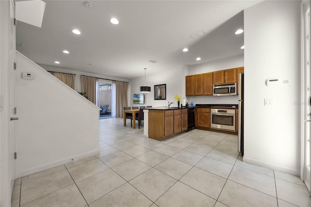 kitchen with light tile patterned flooring, kitchen peninsula, hanging light fixtures, and appliances with stainless steel finishes