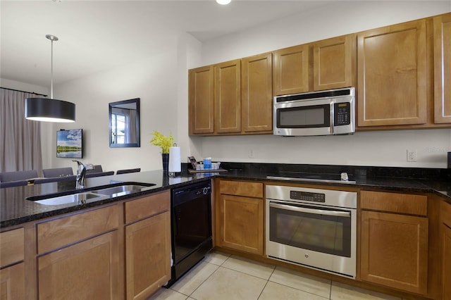 kitchen with sink, stainless steel appliances, dark stone counters, decorative light fixtures, and light tile patterned floors