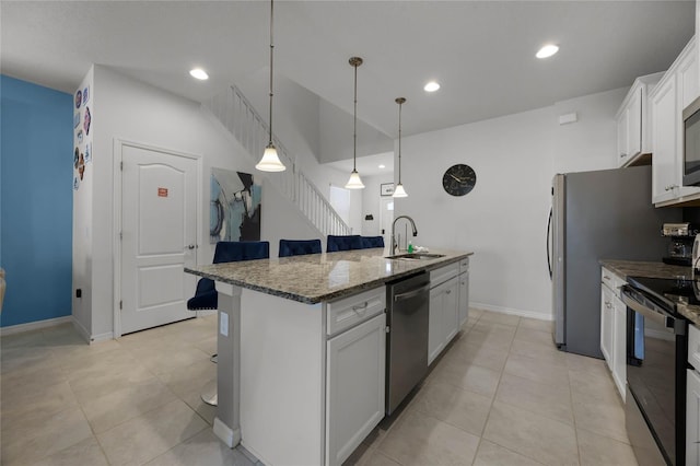 kitchen with white cabinets, sink, an island with sink, appliances with stainless steel finishes, and a kitchen bar