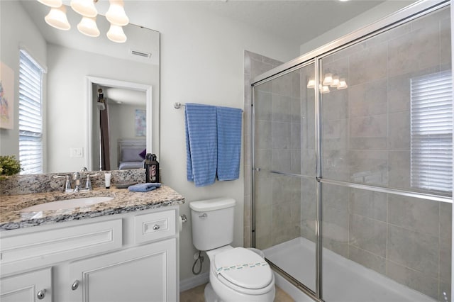 bathroom with vanity, toilet, a shower with door, and a notable chandelier