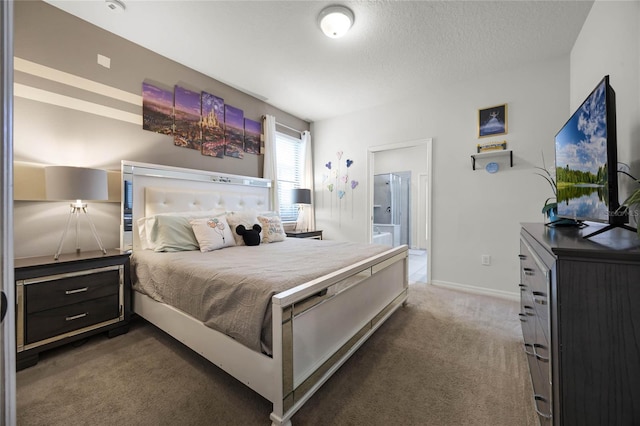 bedroom with dark colored carpet, a textured ceiling, and ensuite bathroom