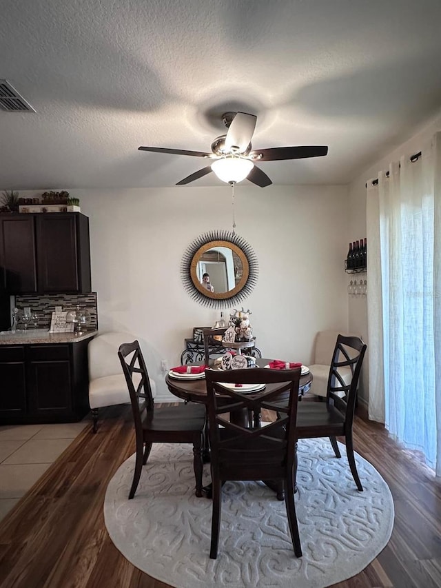 dining room featuring ceiling fan, light hardwood / wood-style floors, and a textured ceiling