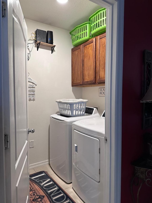 laundry room with cabinets, washing machine and dryer, and tile patterned floors