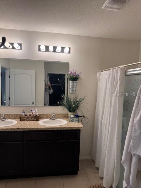 bathroom featuring a shower with curtain, vanity, tile patterned flooring, and a textured ceiling