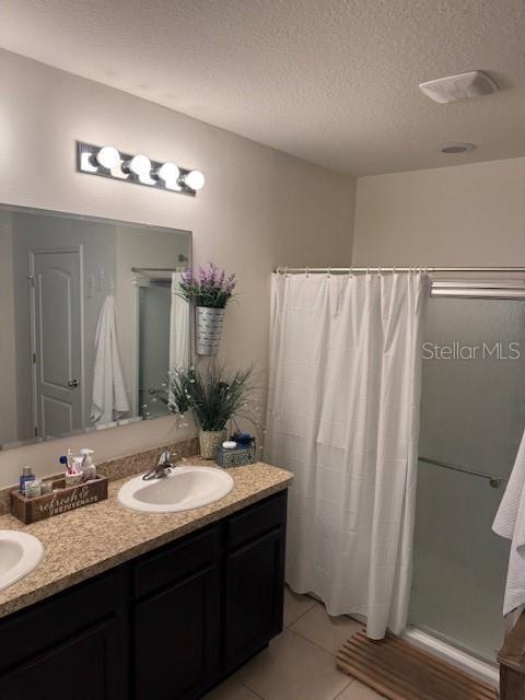 bathroom with vanity, curtained shower, tile patterned flooring, and a textured ceiling